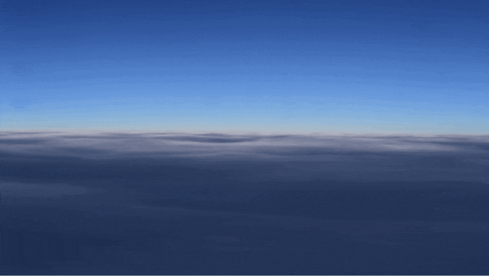 A blue layer of clouds (shot from above from a plane window) slowly turns into a yellow desert dreamscape